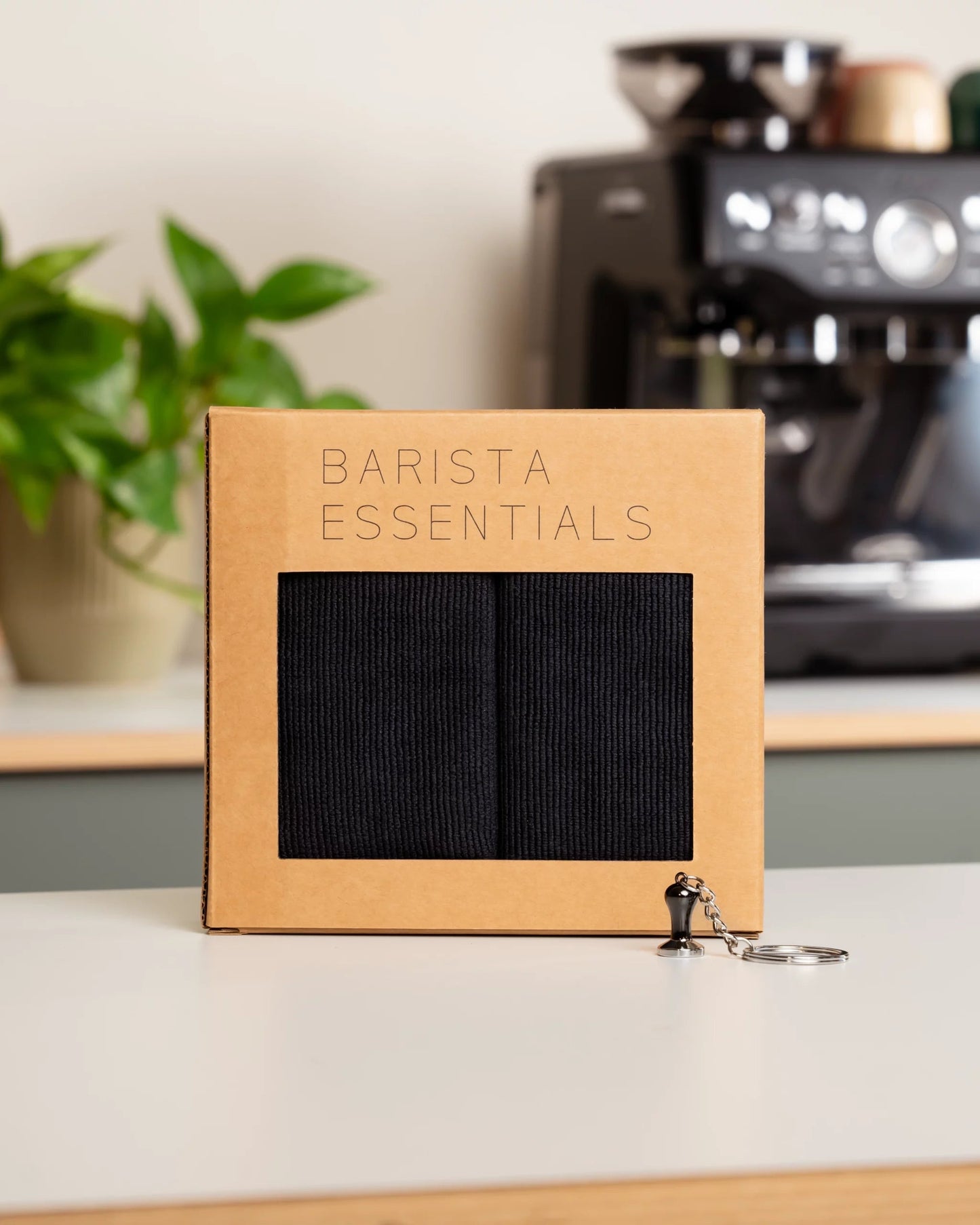 Gift set from Barista Essentials for home baristas, containing black barista cloths and a tamper keyring.