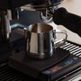 Espresso pitcher under a machine and on a coffee scale