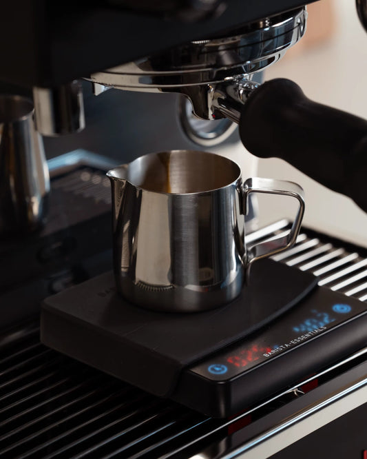 Espresso pitcher under a machine and on a coffee scale