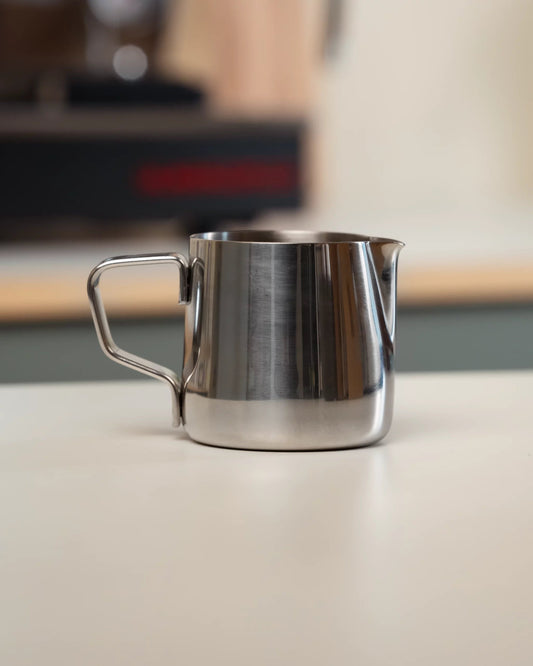 Stainless steel espresso pitcher in a coffee corner