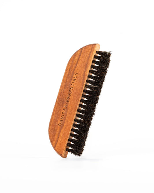 Wooden coffee brush with black bristles and “Barista Essentials” engraved on the handle.